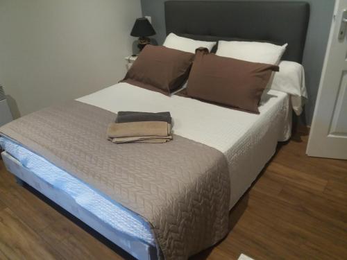 - une chambre avec un grand lit et des oreillers bruns dans l'établissement Gîte Mimi, à Saint-Sulpice-de-Faleyrens