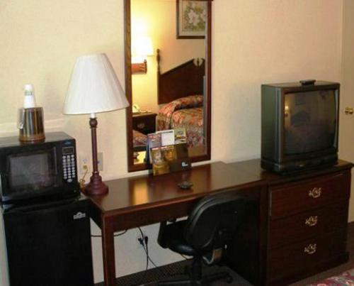 a room with a desk with a microwave and a television at Scottish Inn Maggie Valley in Maggie Valley