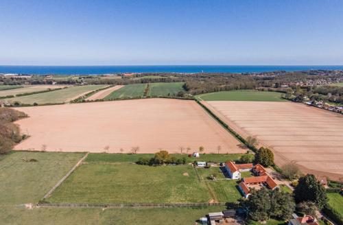 an aerial view of a field and the ocean at Anvil & Stable Cottages in Felbrigg