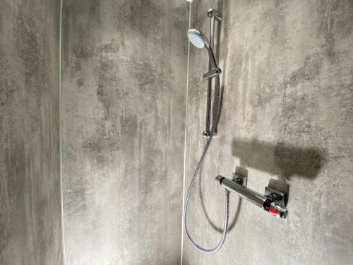 prysznic z głowicą prysznicową na ścianie w obiekcie Irvine Guest House w mieście Irvine