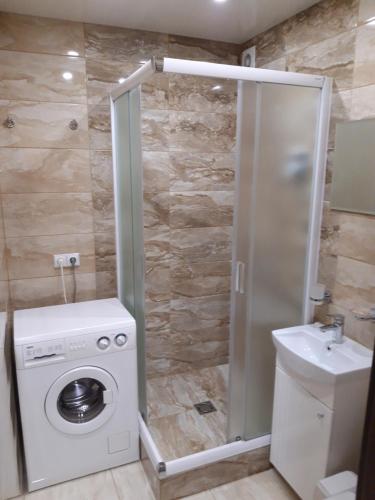 ein Badezimmer mit einer Waschmaschine und einem Waschbecken in der Unterkunft Ferry Terminal Aparts in Klaipėda