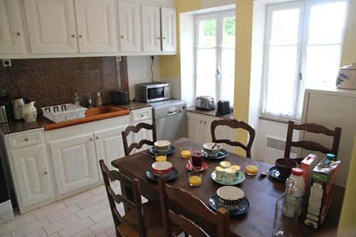 cocina con mesa de madera con sillas y comedor en La Maison et son jardin sur le Canal de Bourgogne, en Ravières