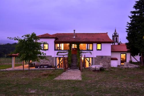 a large white house with a clock tower in the background at Casa da Quinta do Cruzeiro in Fontoura