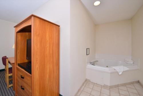 um quarto com uma banheira e um armário de madeira em Super 8 by Wyndham Bedford em Bedford