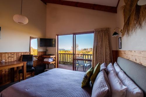een slaapkamer met een bed en uitzicht op een balkon bij Ocean View Chalets in Marahau