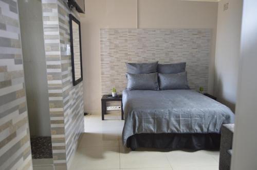 - une chambre avec un lit et un mur en briques dans l'établissement Bluff Marine Drive Self Catering Cottage B, à Durban