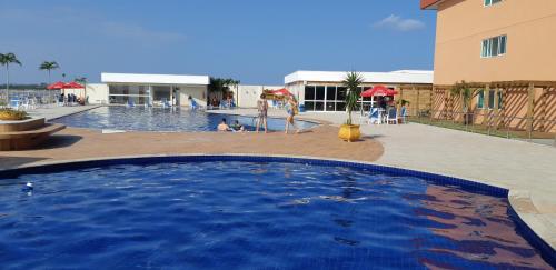 una piscina en un complejo con gente jugando en él en GOLDEN LAKE RESIDENCE en Arraial do Cabo