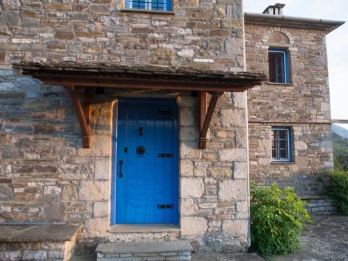 a stone building with a blue door on it at Chariklia Traditional House in Papigko