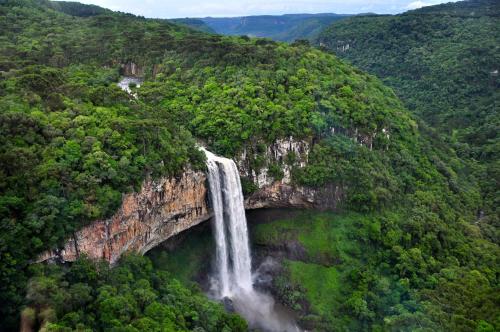 a waterfall on the side of a mountain with trees at Chalé Temático em Pipa de Vinho - Parada da Pipa Chalés in Canela