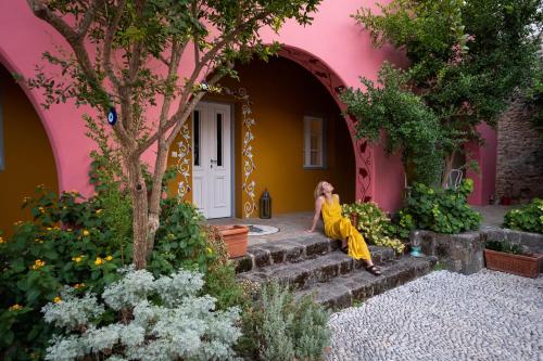 a woman sitting on the steps of a pink house at Saint Artemios Hotel and Oriental Suites in Rhodes Town