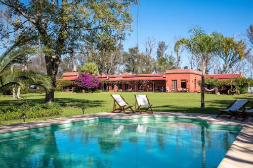 a swimming pool with two chairs and a house at Estancia La violeta in Chajarí