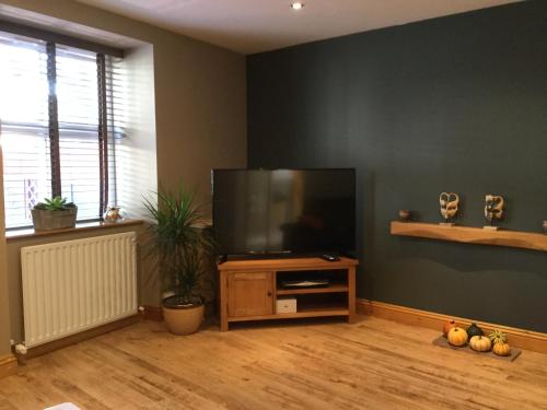 a living room with a flat screen tv on a stand at 6 beili priory in Abergavenny