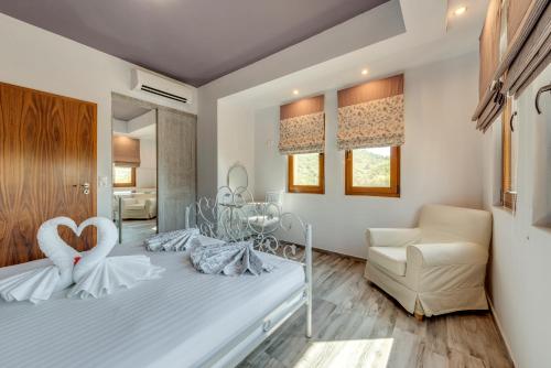 ein Schlafzimmer mit einem weißen Bett und einem Stuhl in der Unterkunft Harmony Deluxe Villas in Theológos