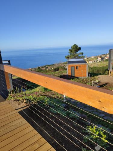 a wooden bench on a deck with a view of the ocean at Calheta Glamping Pods - Nature Retreat in Calheta