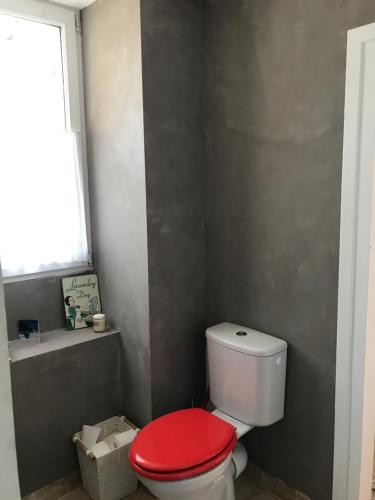 a bathroom with a toilet with a red lid at Chez leo in Marboué