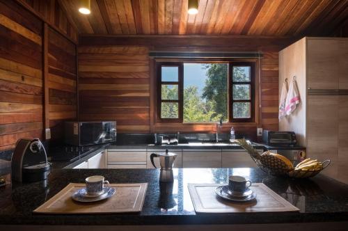 a kitchen with wooden walls and a counter with two cups at Casinha de Madeira no Vale do Capão in Vale do Capao