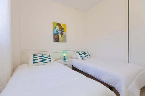two twin beds in a room with white walls at Apartamento Jumilla Vista Mar 23 in Playa del Ingles