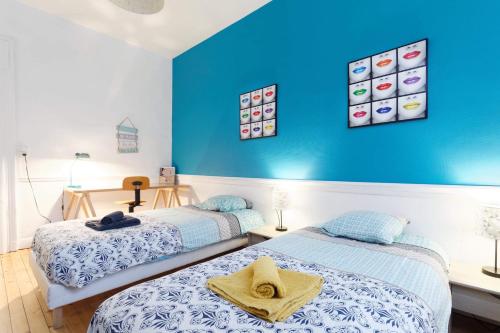 - 2 lits dans une chambre avec un mur bleu dans l'établissement L’atelier de Loane, au Havre