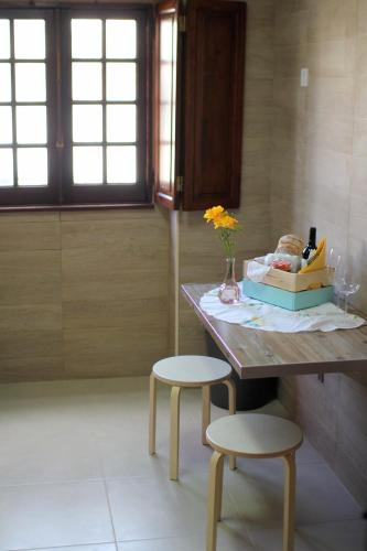 a table with a vase of flowers and two stools at Vila Mafra - Grill Terrace in Mafra