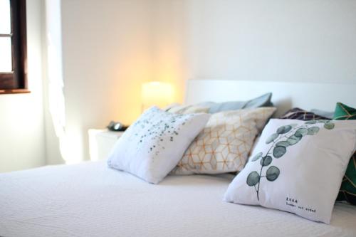 a white bed with pillows on top of it at Vila Mafra - Grill Terrace in Mafra