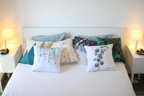 um quarto com uma cama branca com almofadas em Vila Mafra - Grill Terrace em Mafra