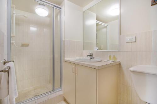 a white bathroom with a sink and a shower at Meridian Tower Kirra Beach in Gold Coast