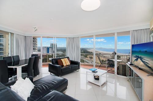 a living room with a couch and a large screen tv at Meridian Tower Kirra Beach in Gold Coast