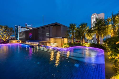 a large swimming pool in a city at night at XQ Pattaya Hotel in Pattaya