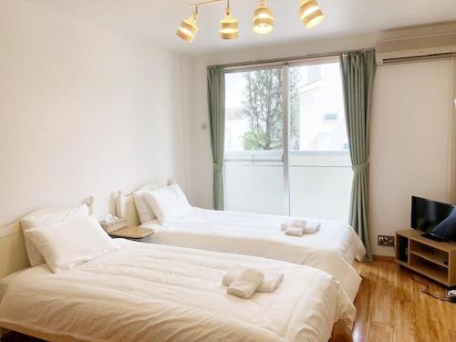 福岡市にあるラ・フィットヤマト103の窓付きの客室で、白いベッド2台が備わります。
