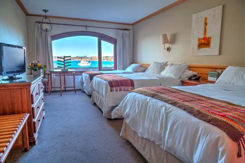 um quarto de hotel com duas camas e uma televisão em Hotel Cabaña Del Lago Puerto Varas em Puerto Varas