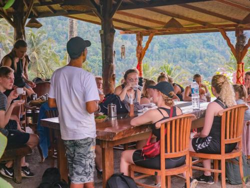 eine Gruppe von Personen, die in einem Restaurant an Tischen sitzen in der Unterkunft Puri Sunny Camp in Munduk