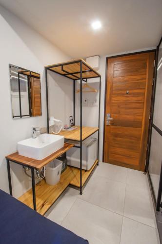 a bathroom with a sink and a wooden door at Sathu Hotel in Chiang Mai