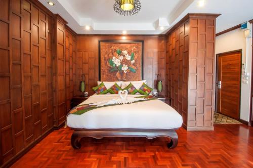 a bedroom with a bed with a painting on the wall at Sathu Hotel in Chiang Mai