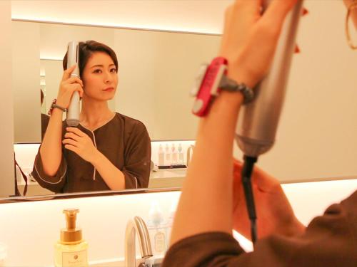 a woman taking a picture of herself in a bathroom mirror at LEO YU Capsule Hotel Nishifunabashi in Funabashi