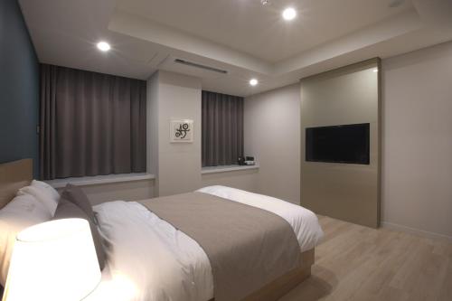 a bedroom with a bed and a flat screen tv at Lamer Hotel in Busan