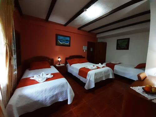two beds in a room with red walls at Suymar Ecolodge Galapagos in Puerto Ayora