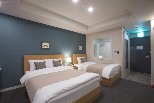 two beds in a room with blue walls at Lamer Hotel in Busan
