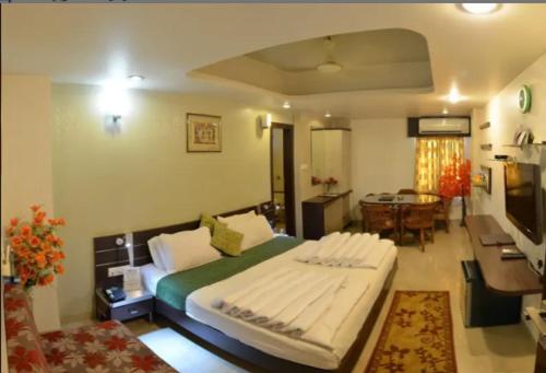 a bedroom with a large bed and a dining room at Hotel Shree Vatika in Bhopal