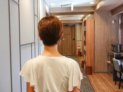 a woman standing in a hallway looking at a room at LEO YU Capsule Hotel Nishifunabashi in Funabashi