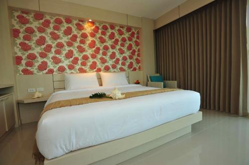 a bedroom with a large white bed with a floral wall at Chalong Beach Front Residence in Rawai Beach