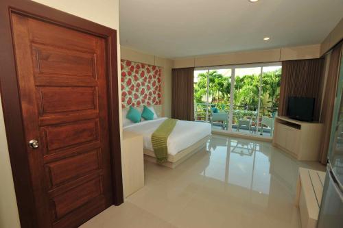 a bedroom with a bed and a balcony with a television at Chalong Beach Front Residence in Rawai Beach