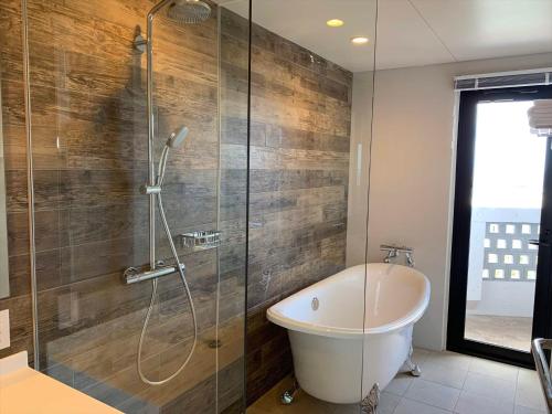 a bathroom with a shower and a bath tub at Yomitan Condhotel ND in Yomitan