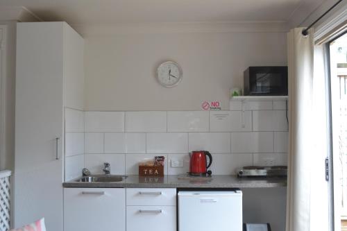 a white kitchen with a sink and a microwave at The Lighthouse in Auckland