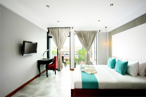 a bedroom with a bed and a desk and a television at CENTRAL BLANCHE Residence in Siem Reap