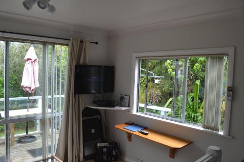a living room with two windows and a television at The Lighthouse in Auckland