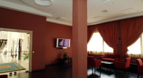 a room with red walls and red chairs and a tv at Atlas Orient in Oujda