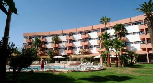 a large building with a swimming pool and palm trees at Atlas Orient in Oujda
