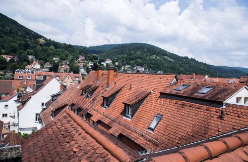 Blick auf die Dächer einer Stadt mit Bergen im Hintergrund in der Unterkunft Hotel am Rathaus in Heidelberg