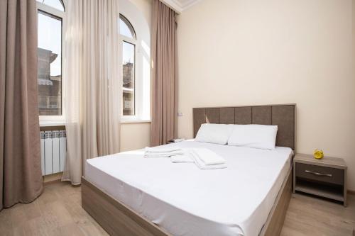 a bedroom with a large white bed and two windows at Stay Inn Apartments at Mashtots Avenue 5A in Yerevan