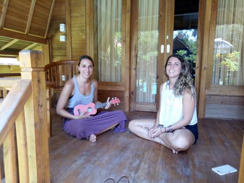 two girls sitting on the floor of a cabin with a guitar at Halumba Eco Villa Bali in Tejakula